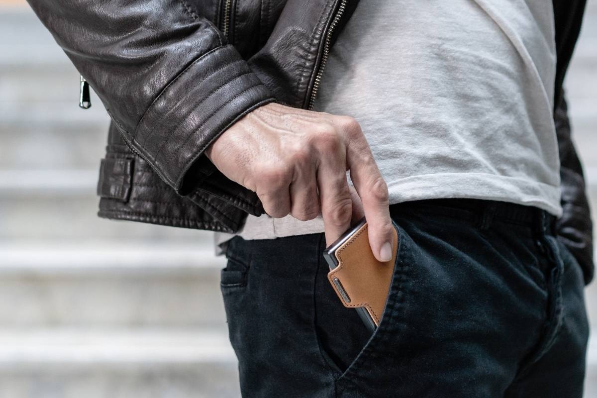 Uomo che mette il mini portafoglio nella tasca davanti dei pantaloni