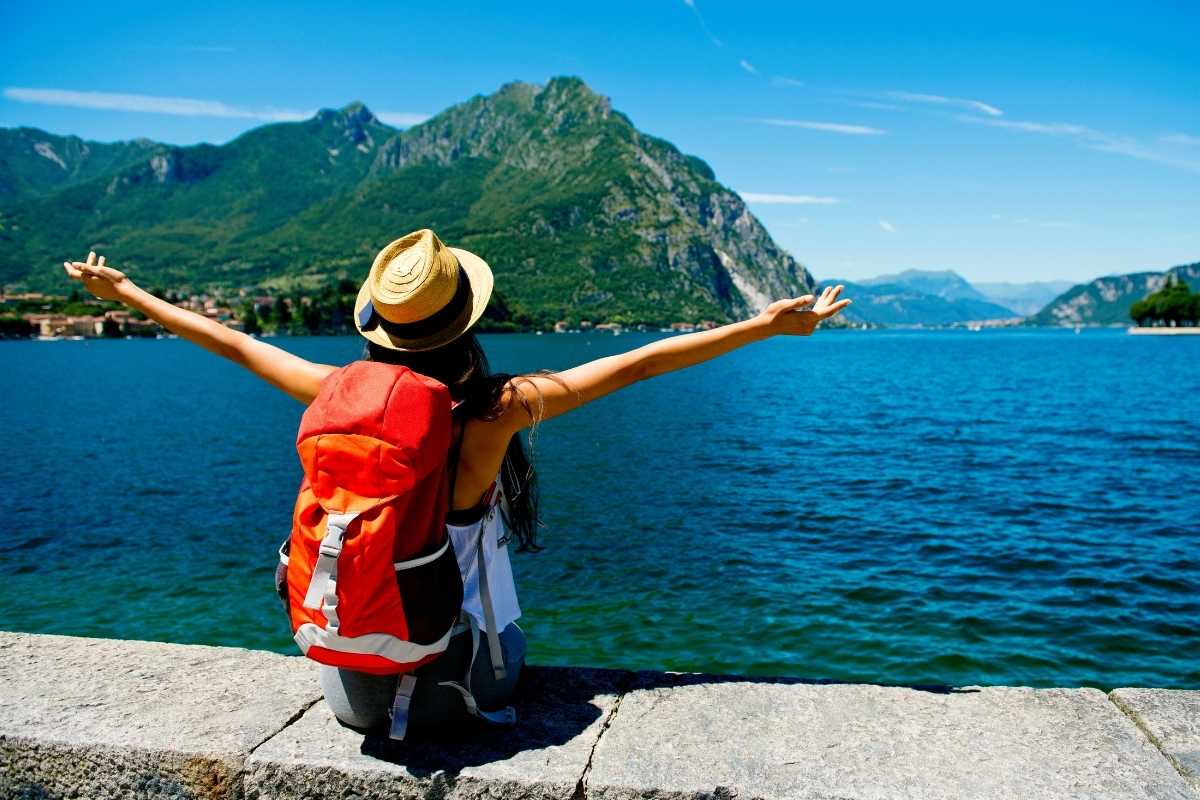 Ragazza in viaggio seduta ad ammirare un lago