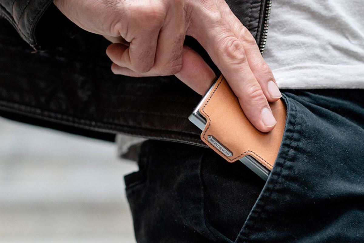 A man sliding a mini wallet into his pants pocket